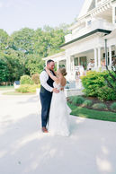 Bride and groom outside a white house with a wraparound porch
