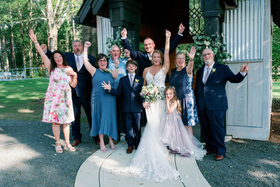 Family and wedding party cheering with raised arms outside the chapel