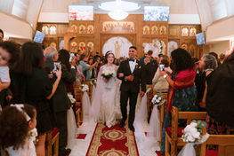 Bride and groom at the altar of an ornate church with guests along the aisle