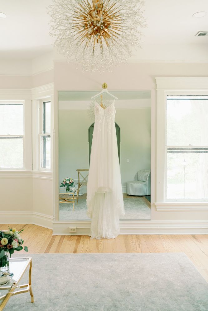 Wedding dress hanging in a bright room beneath a starburst chandelier