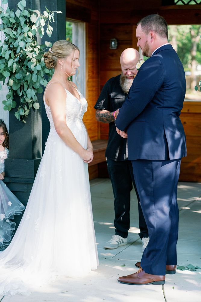 Bride and groom exchanging vows beneath a floral arch in a wooden chapel