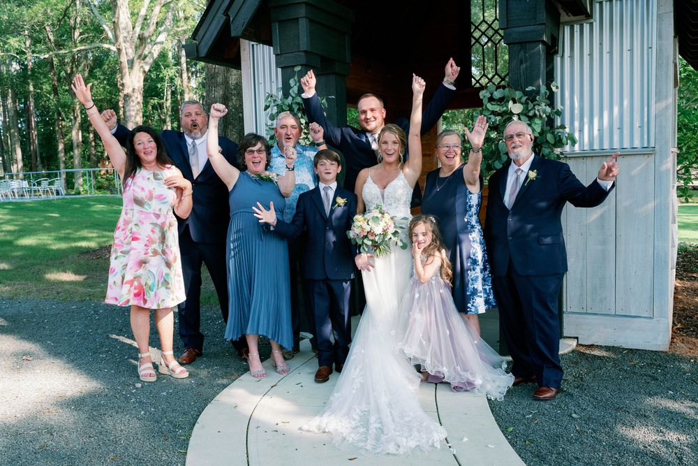 Family and wedding party cheering with raised arms outside the chapel