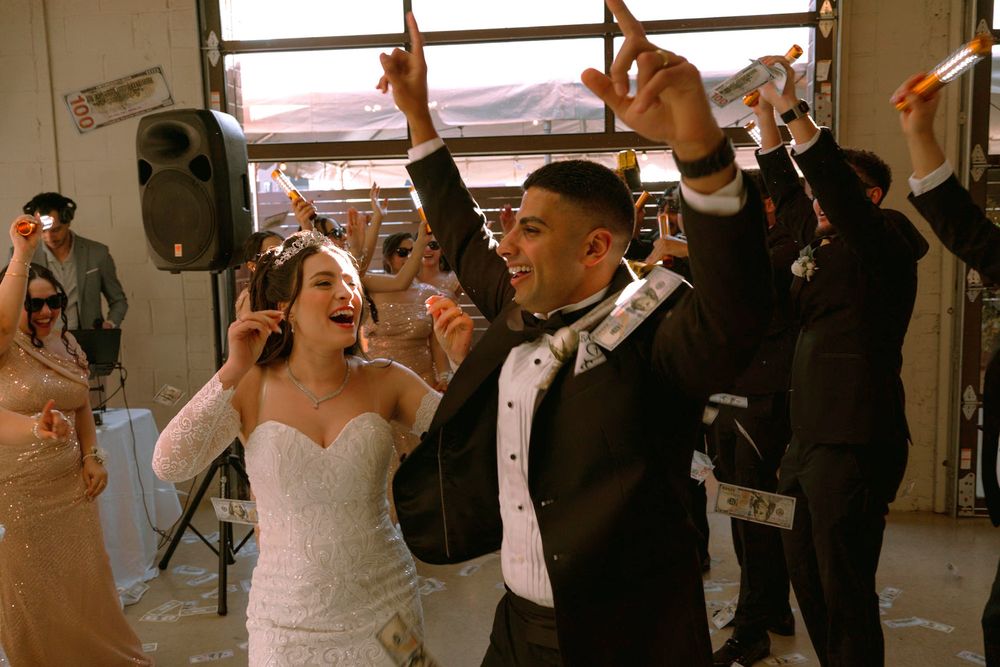 Guests dancing with raised hands around the couple at the reception