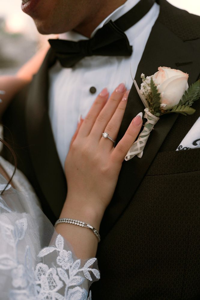 Close-up of the bride's ring hand resting on the groom's tuxedo lapel