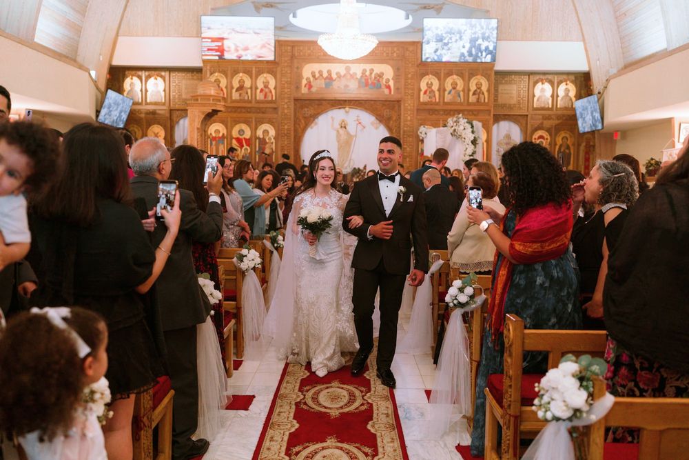 Bride and groom at the altar of an ornate church with guests along the aisle