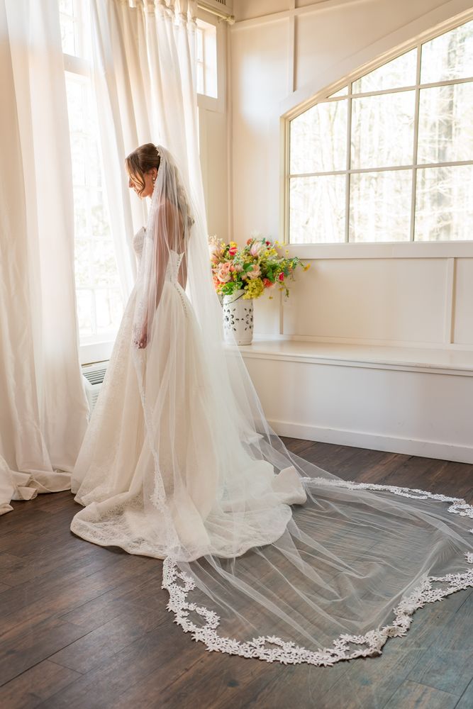 The bride at a tall window, her veil and train spread across the floor