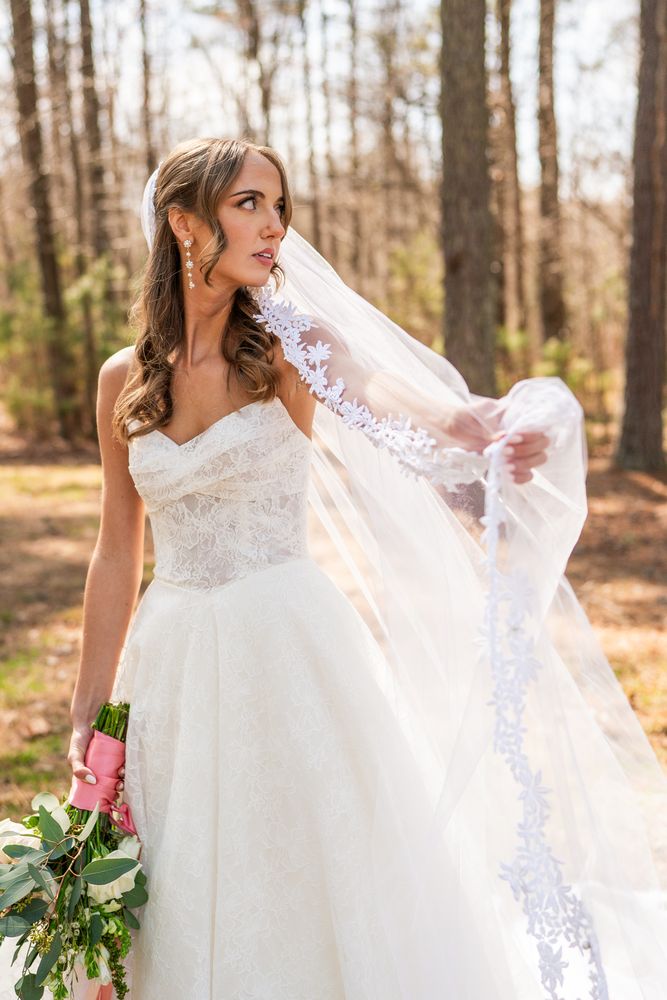 The bride holding her veil out to the side in the woods
