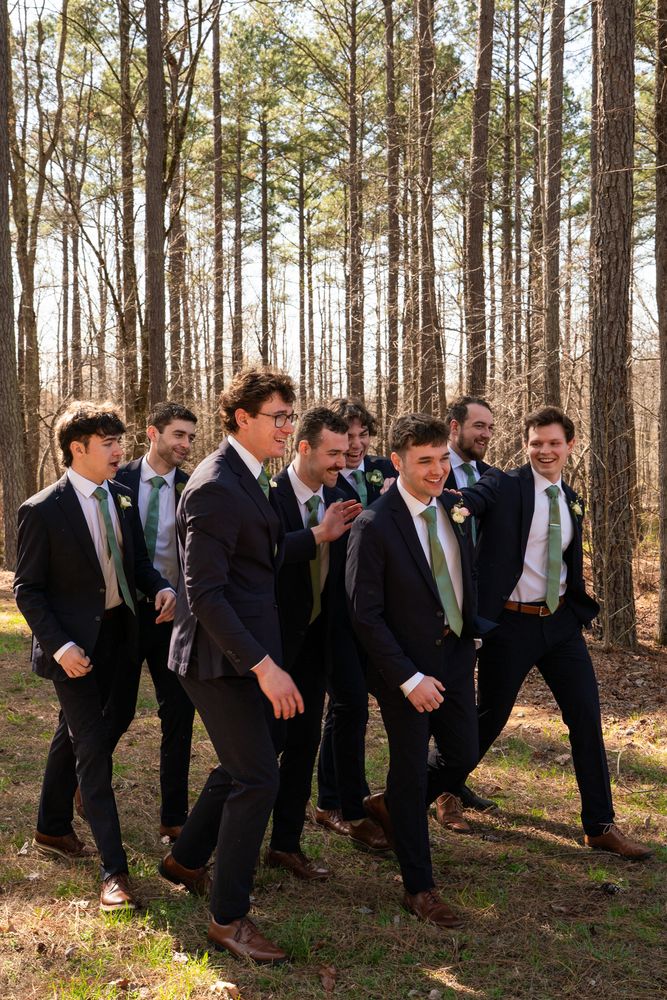 The groomsmen walking together through the pine woods