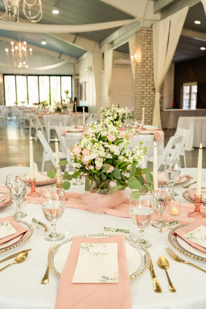 Reception table set with white florals and a coral runner under a chandelier
