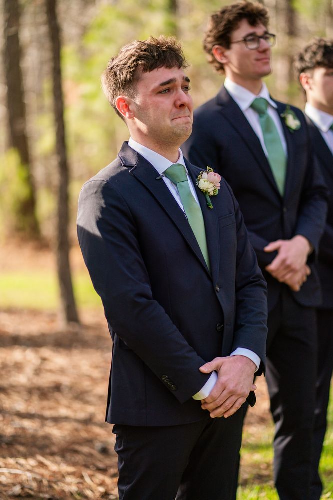 The groom watching the aisle, his groomsmen behind him