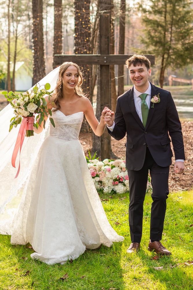 The couple hand in hand on the grass after the ceremony