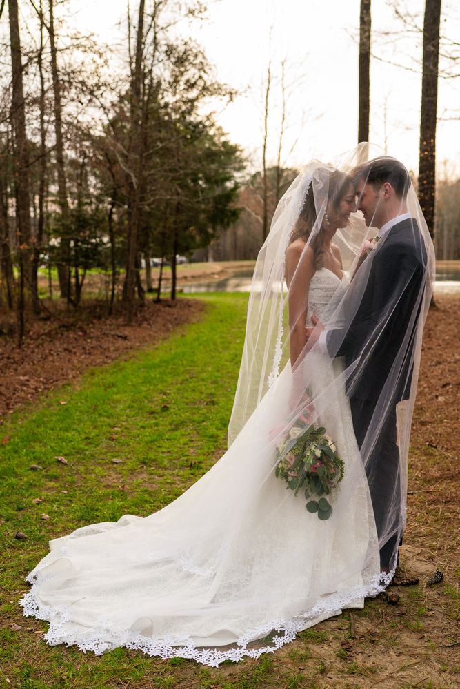 The couple kissing beneath the veil, her train spread along the path