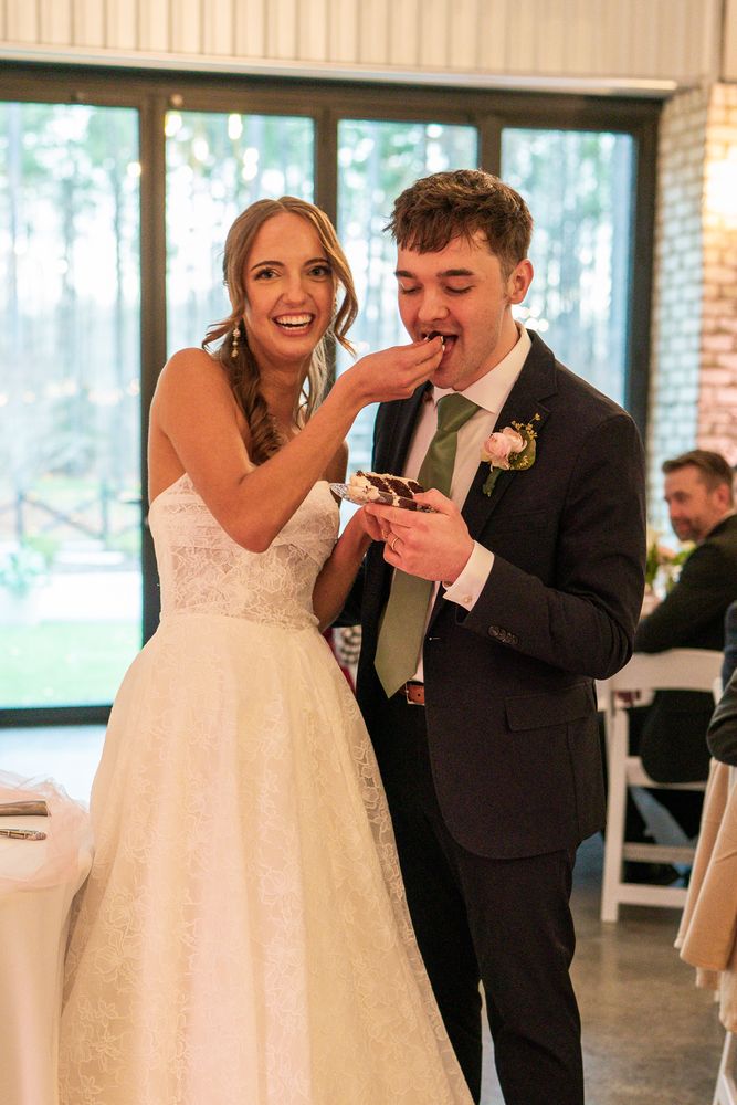 The couple feeding each other cake, both laughing